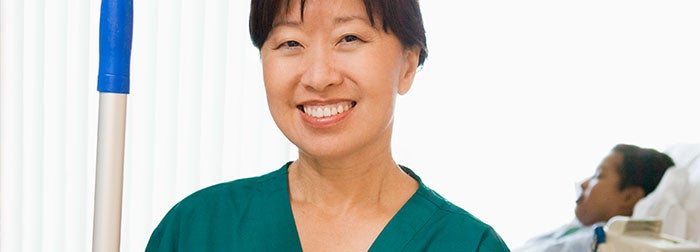 Environmental Services Technician smiling with a patient in the background