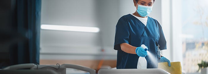 Environmental Services Technician spraying down a medical bed